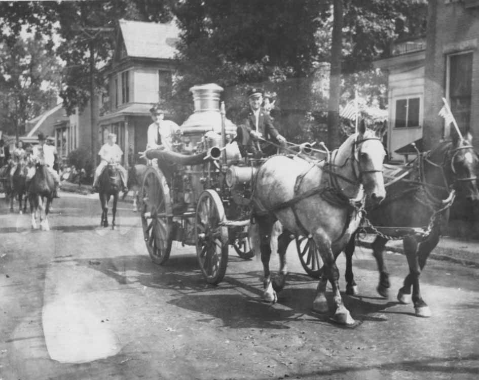 Firemen riding Engine No .2 during a procession, 1960