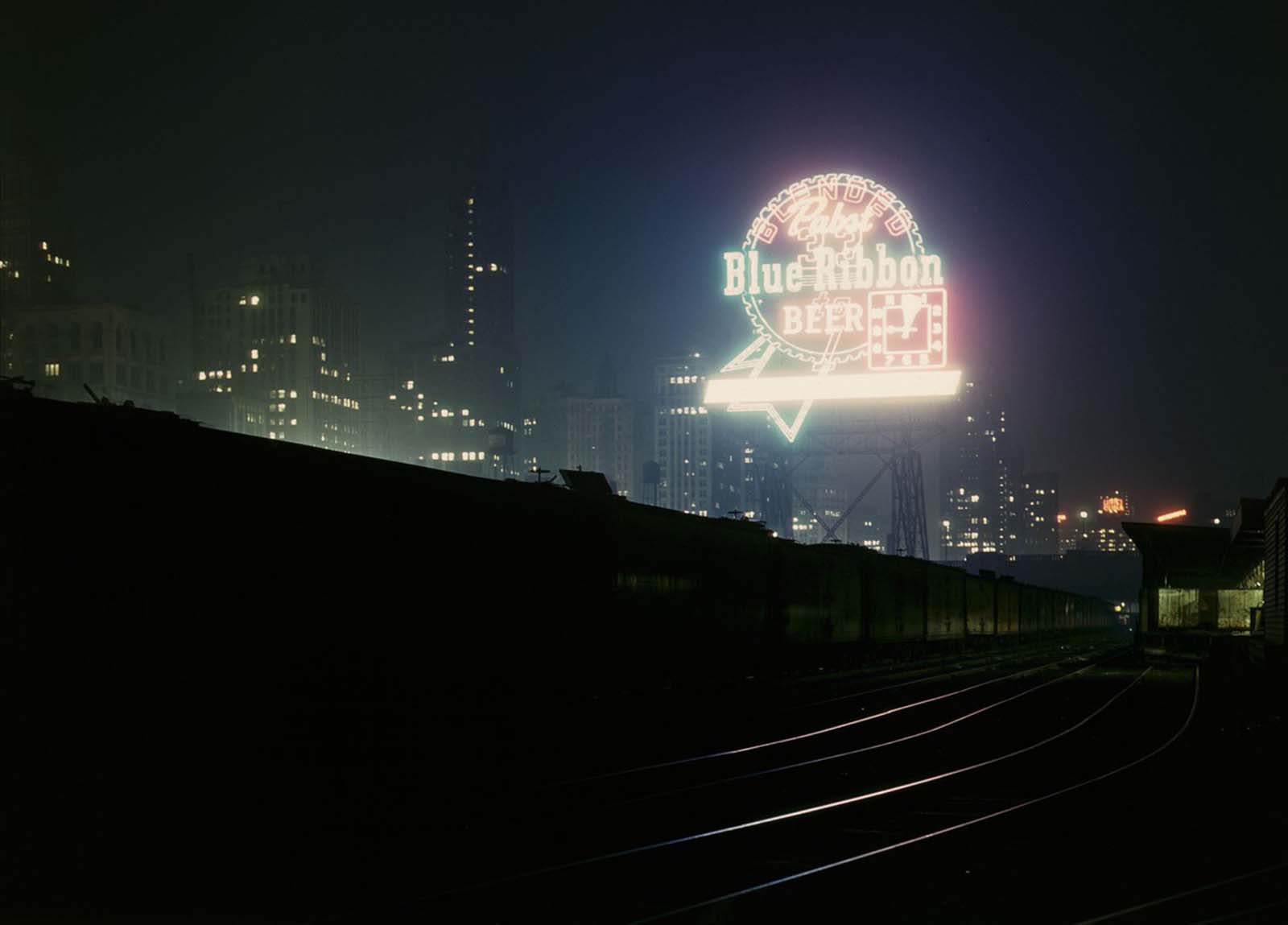 The night is lit up by a giant Pabst Blue Ribbon sign above Chicago’s South Water Street freight terminal in April 1943.