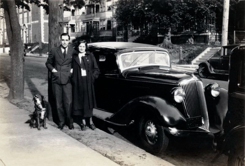 A stylish young couple and their dog posing with a 1933 Graham Blue Streak Sedan in an middle class neighborhood.