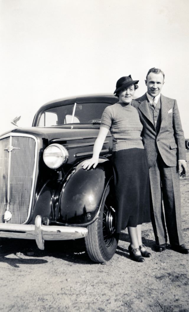 A stylish couple posing with a 1935 Chevrolet Master Deluxe in late afternoon sunshine, circa 1936