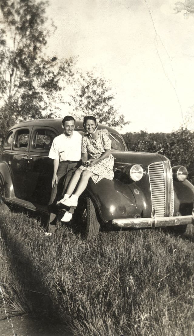 A cheerful couple posing with a 1937 Dodge Sedan on a sunny summer afternoon, somewhere in Canada, 1938