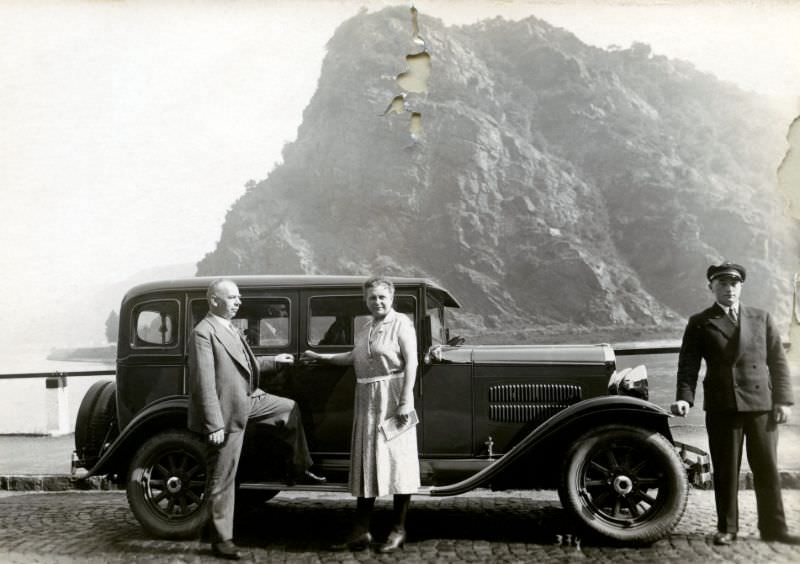 En elderly couple and their chauffeur posing with an 1930 Essex Sedan at Lorelei Rock on the bank of the River Rhine, 1930