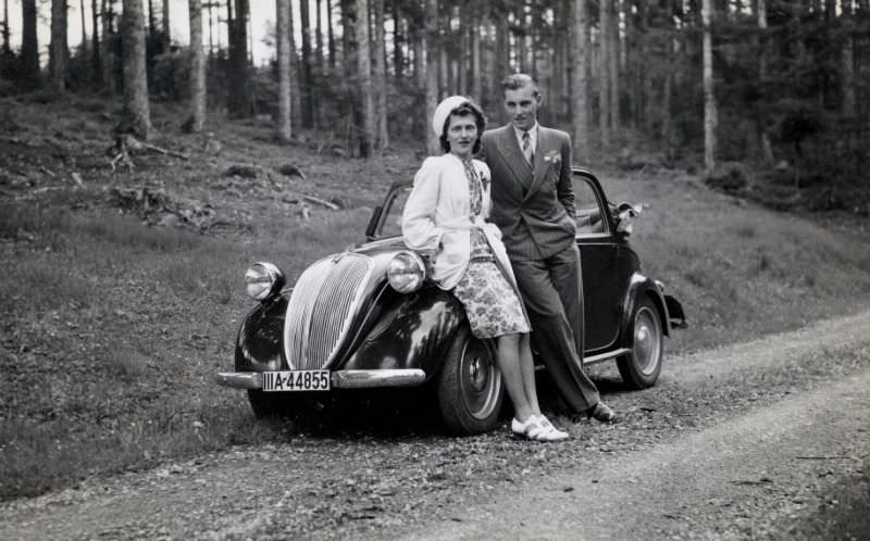 A fashionable couple posing with a Fiat 500 A on a gravel road in the countryside. The car is registered in the city of Stuttgart, 1939