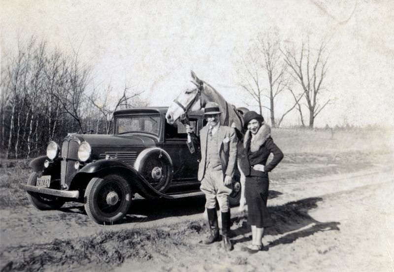 A well-to-do couple posing with their horse and their 1932 Willys-Overland Sedan on a sunny winter's day.