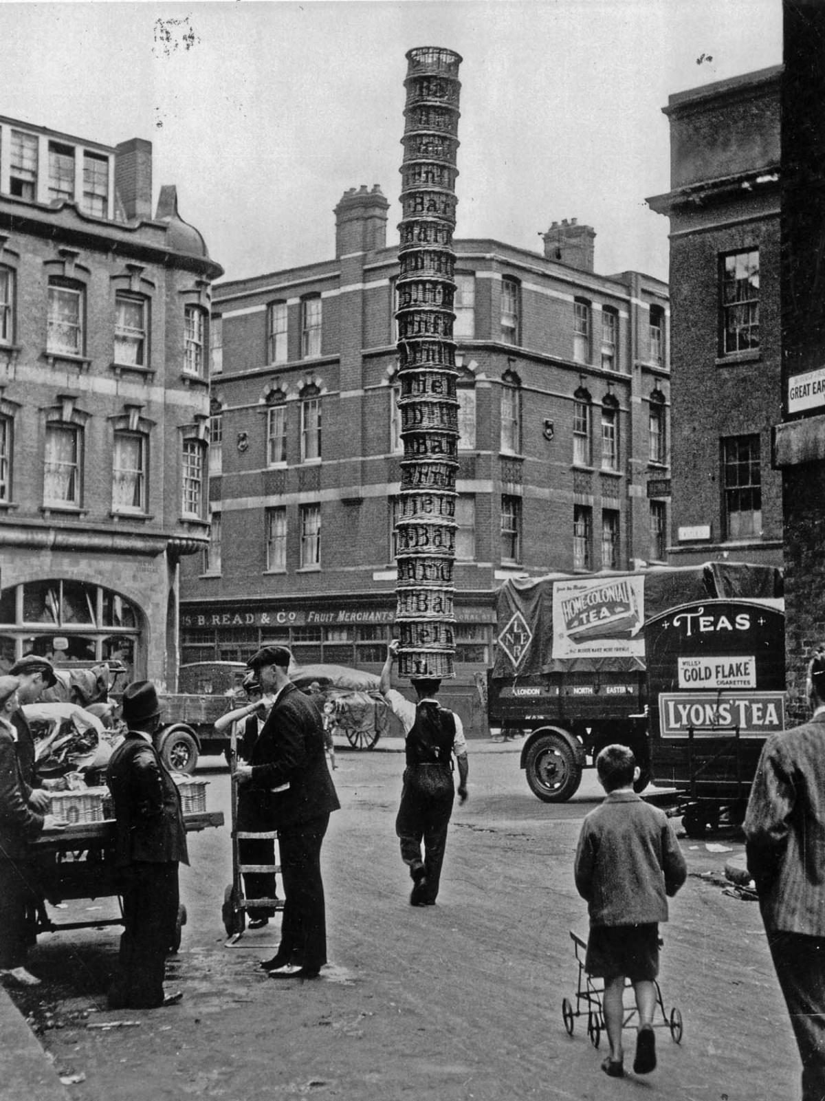 A porter at Covent Garden Market, London, carries twenty baskets on his head, 1925.