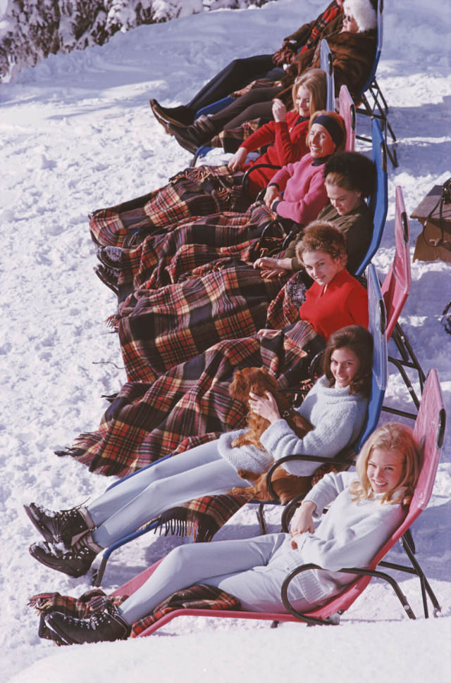 A group of women reclining on the snow in Gstaad with rugs covering their knees, 1963.