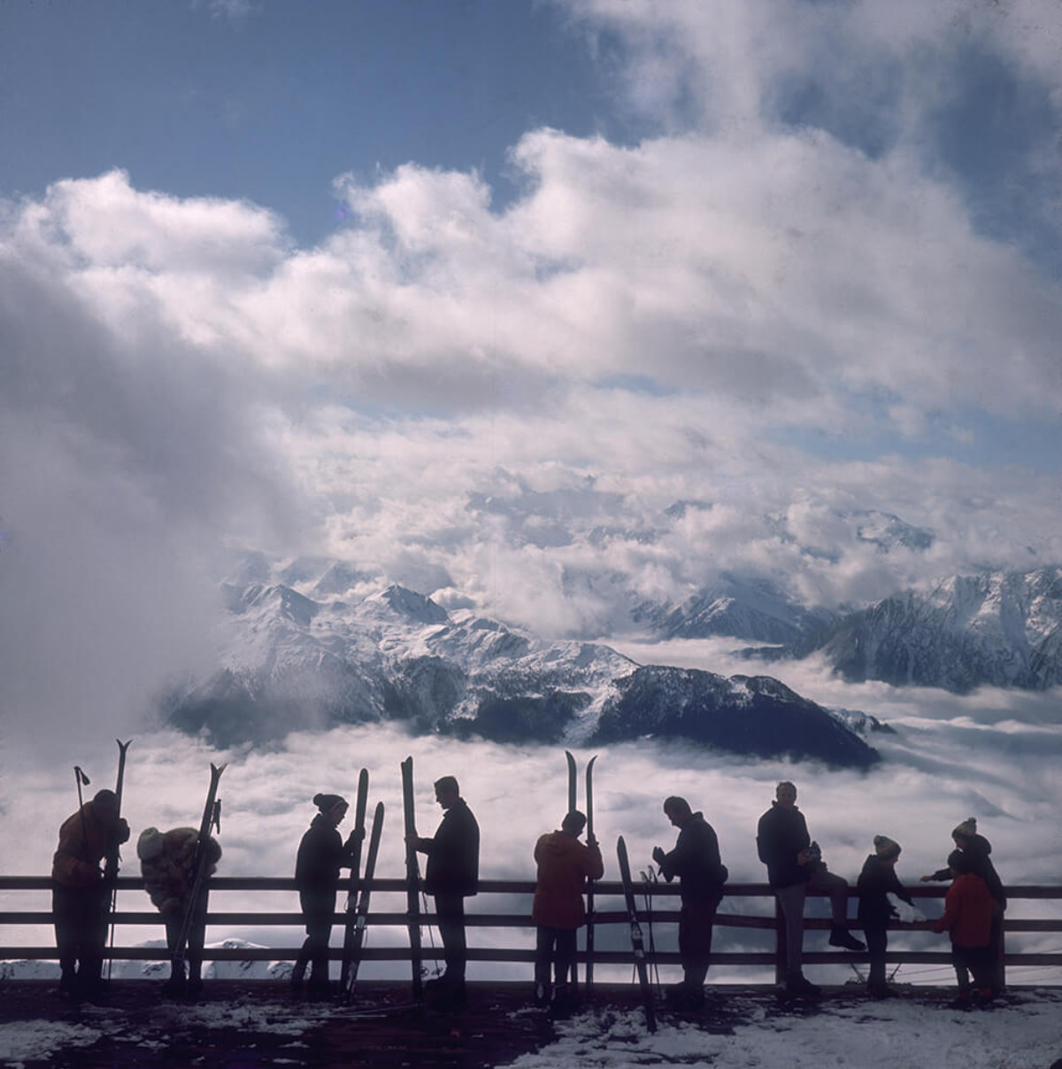 Skiers admire the view across a valley of clouds at Verbier, 1964.