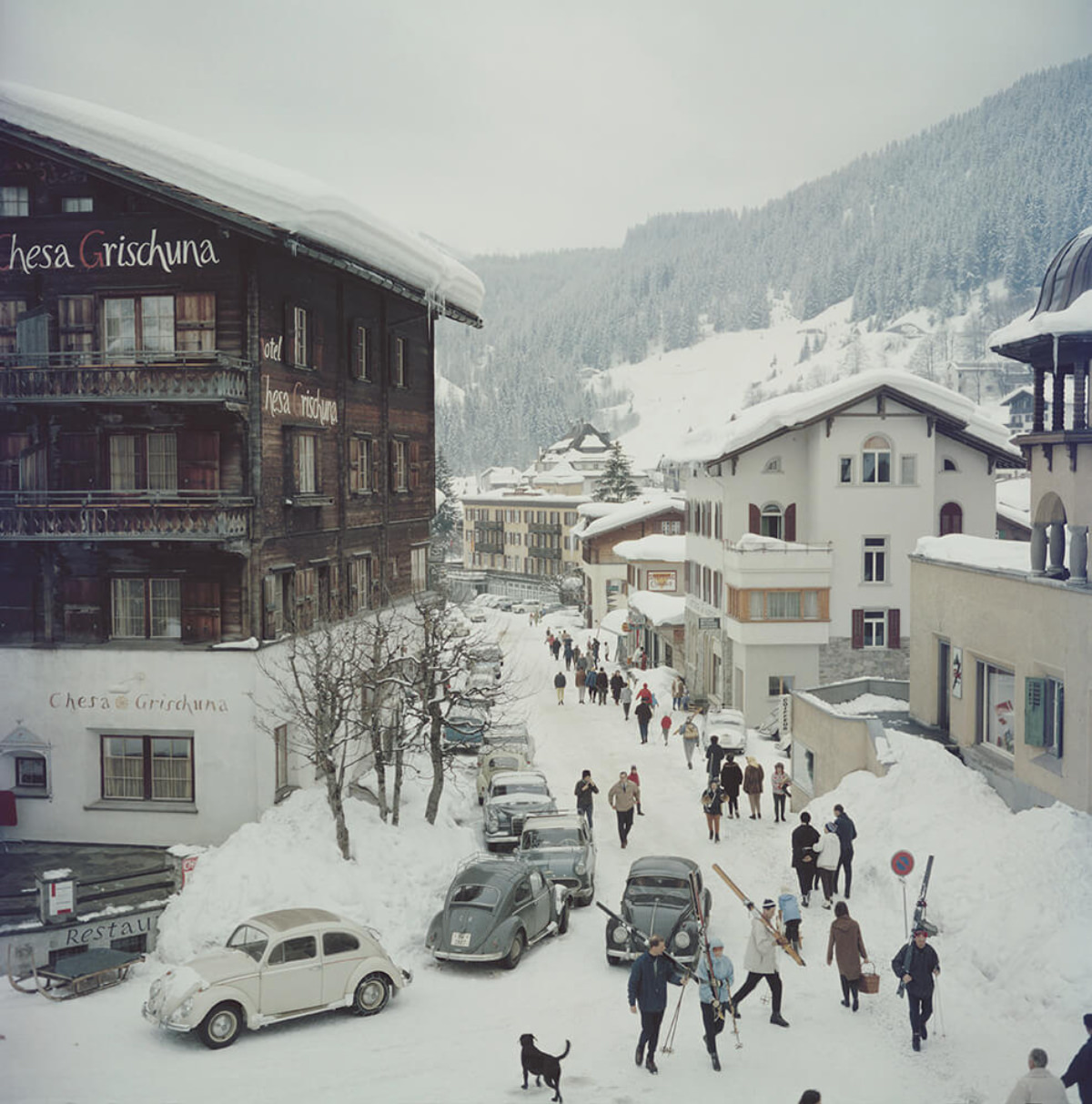 Skiers pass by the Hotel Chesa Grischuna in Klosters, 1963.