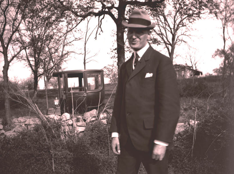 A man at a residence with an electric car, Nashville, 1910s