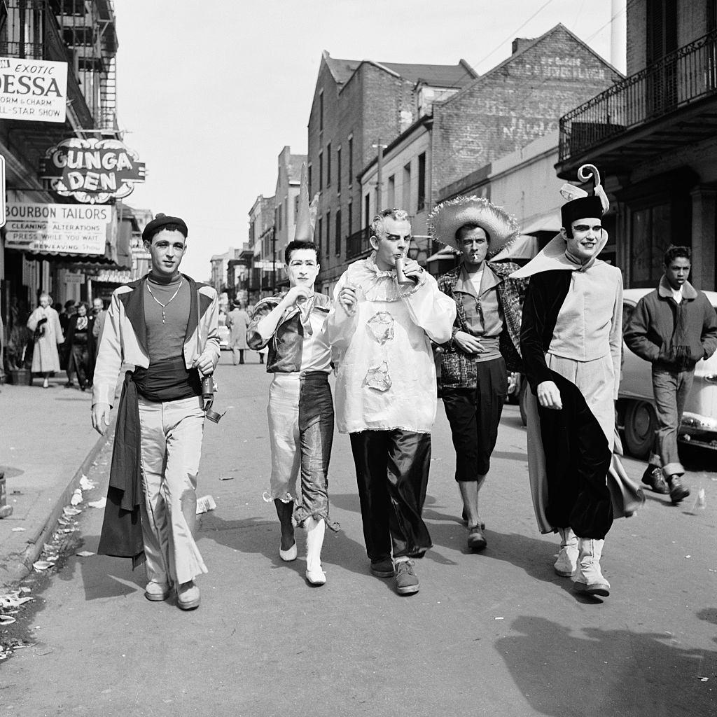 Costumed figures walk down Bourbon Street during Mardi Gras, New Orleans, 1950s.