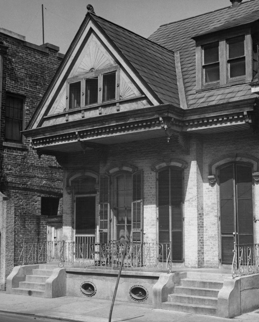 The little house with its high peaked roof meekly rests amidst Bourbon Street night clubs, 1955.