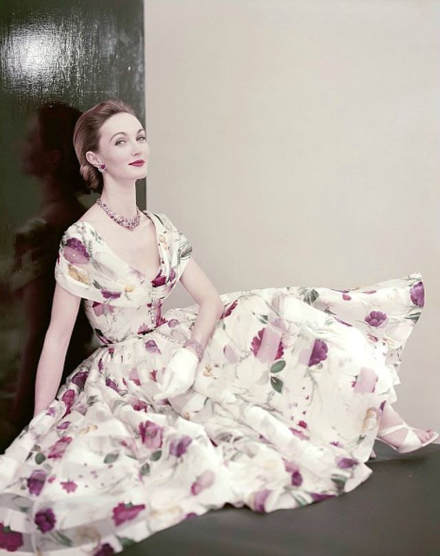 Evelyn Tripp wearing a dress of floral printed white silk organdy with a beaded necklace and bracelet of tourmalines and diamonds, 1955