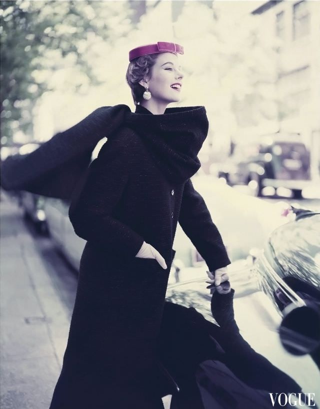 Model wearing narrow long wool woven black coat with a stole and tambourine hat, 1953