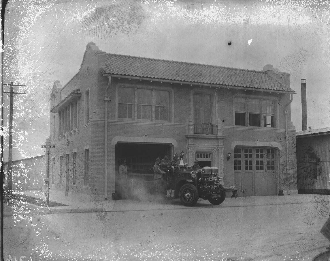 Fire Station No. 11 at the corner of Frio and Matamoros Streets with firemen and a fire truck on the drive, 1925