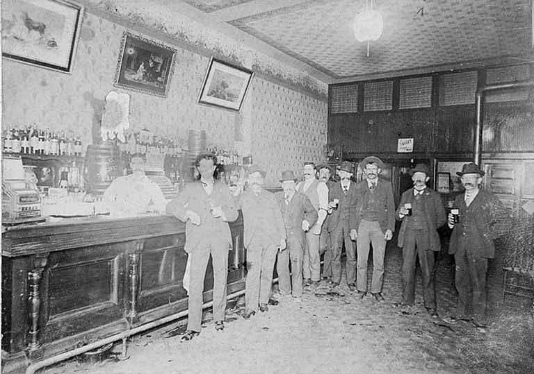 Saloon interior showing men standing at the bar, Occidental Ave. and Washington St., 1895