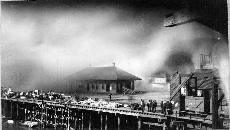 Fire of June 6, 1889 showing goods piled on the dock near the Seattle, Lakeshore & Eastern Railway Depot as smoke from the fire fills the background