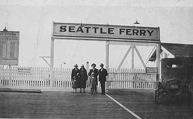 People posing with Seattle Ferry sign on Medina ferry dock, Medina, 1925