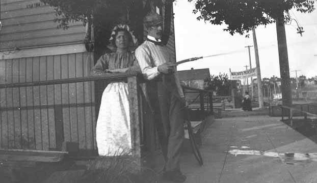 William Cruse on sidewalk with hose, Bellevue, 1915