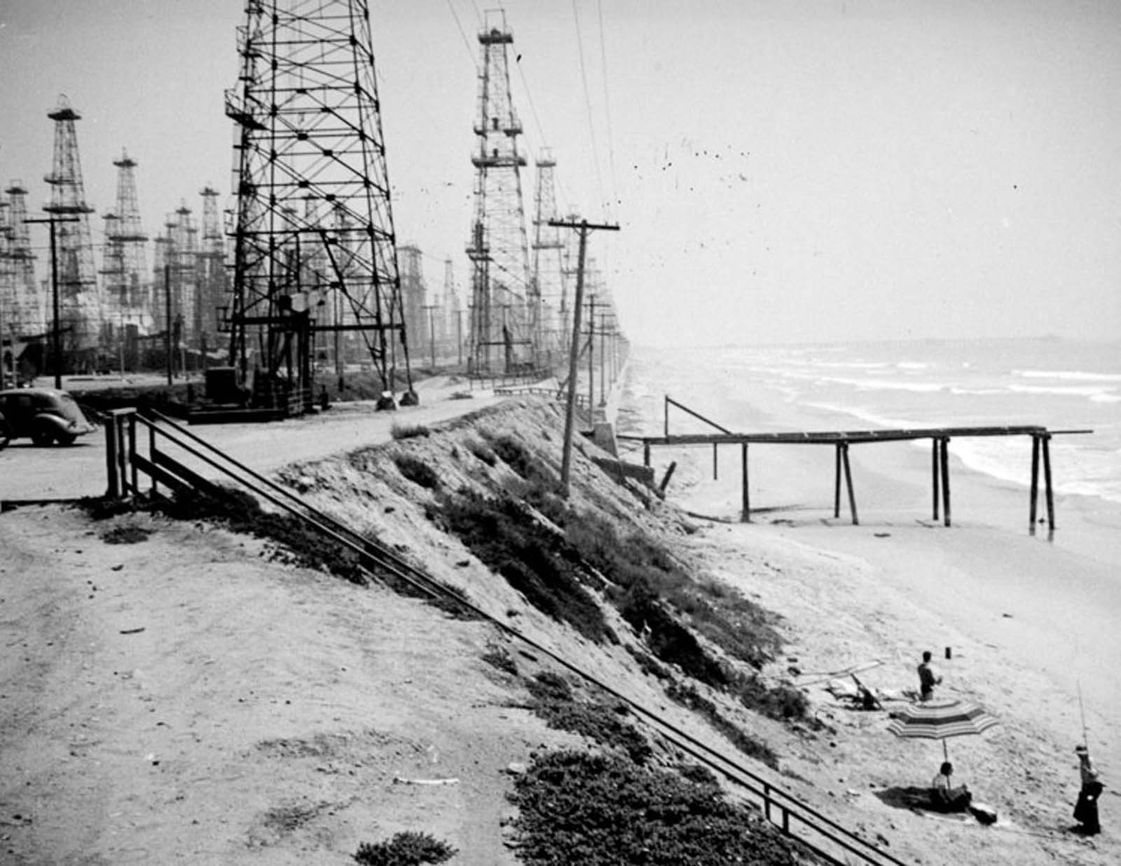 Oil derricks and bathers on Huntington Beach, 1937