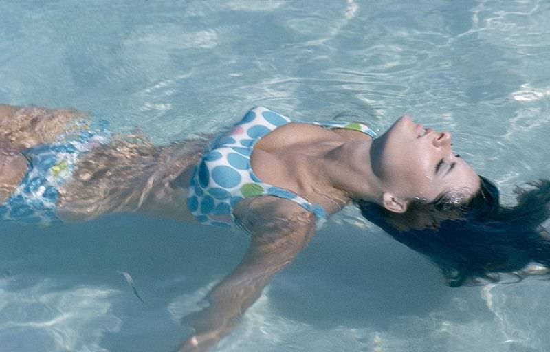 Model is wearing a white bikini with blue, red and green poka dots by Rose Marie Reid, 1965