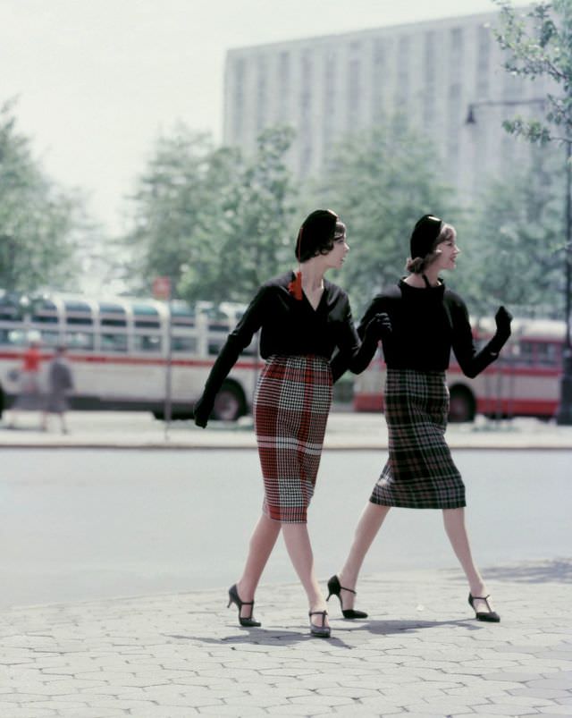 Two models sporting plaid skirts and blouses of black worsted wool, with black berets, Vogue, August 1958