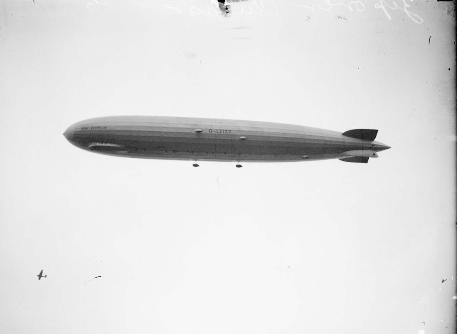 The Graf Zeppelin flies over Chicago, Illinois. An airplane is visible below the Zeppelin on the lower left half of the image.
