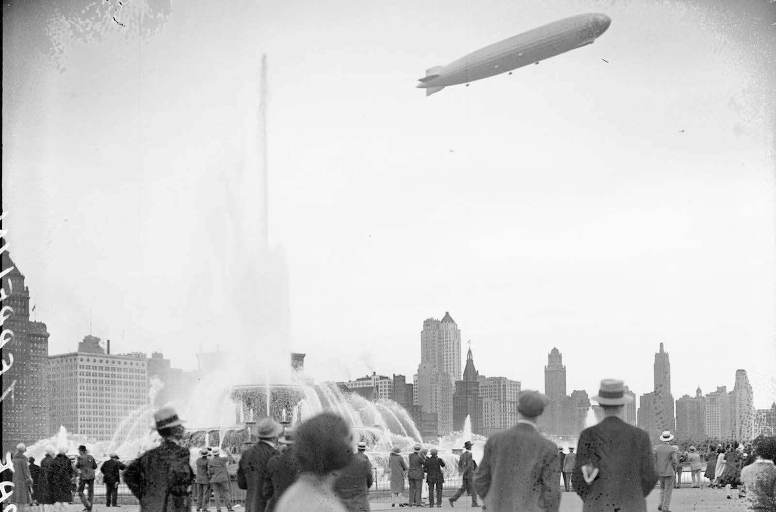 View of the Graf Zeppelin at an angle flying over Buckingham Fountain in Grant Park.