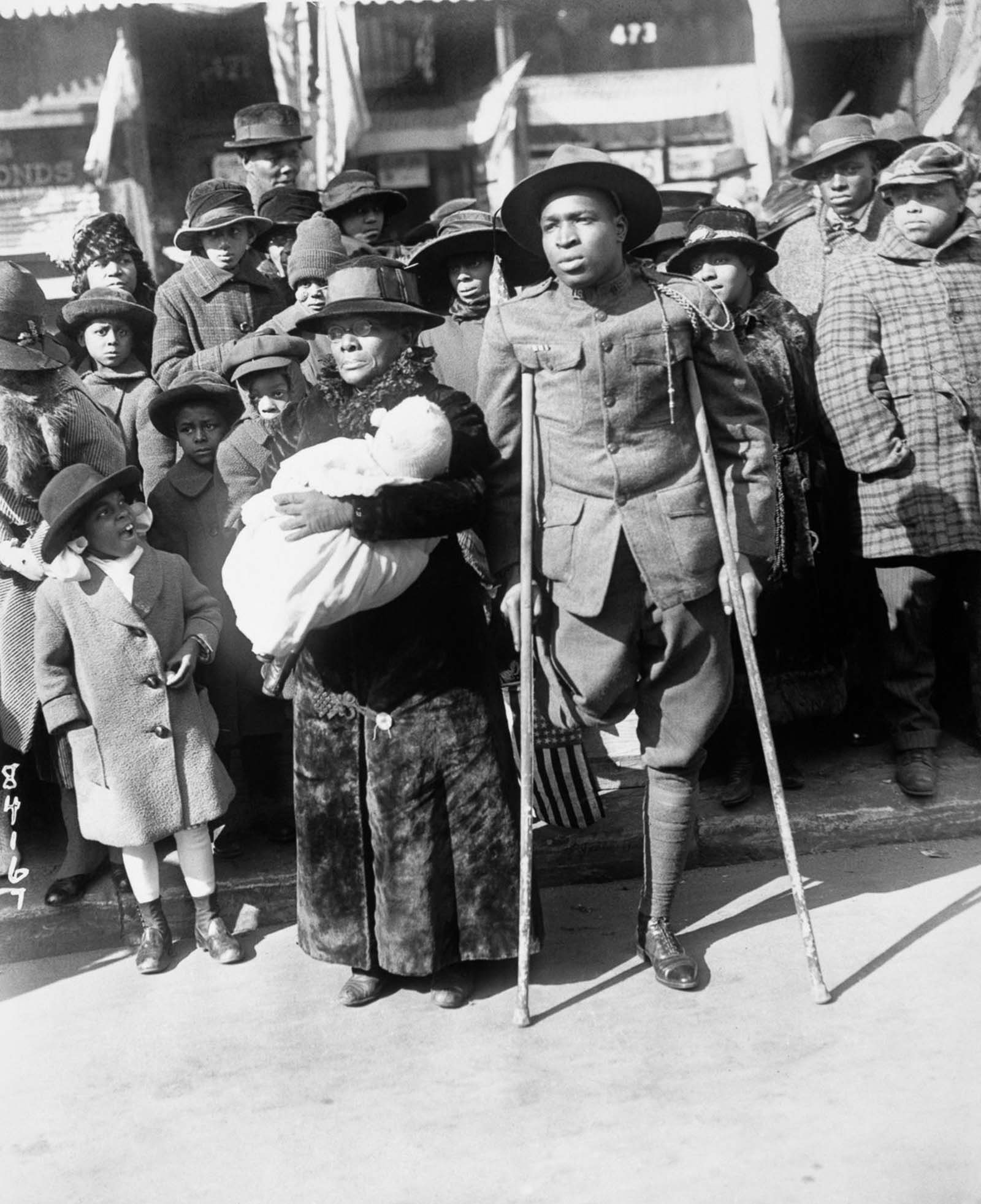 A wounded veteran watches the victory parade of the 369th.