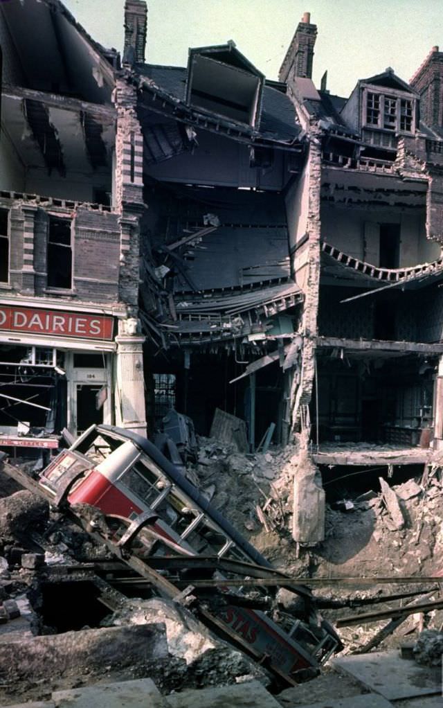 Wreckage of a bus leaning into a huge crater in front of bombed out buildings, a result of German aerial blitz attacks during the Battle of Britain, October 15, 1940