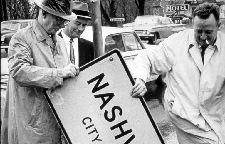 Mayor Beverly Briley and others removing city limit sign, 1962