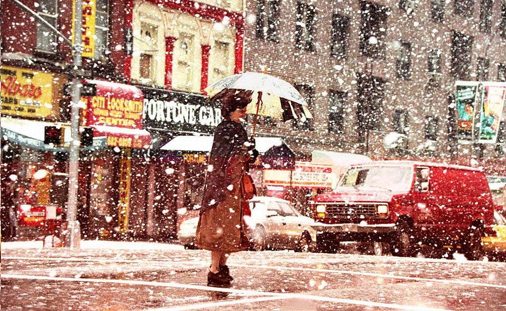 A pedestrian walks across the street in theavy snow 29 March during a spring snowstorm in New York.