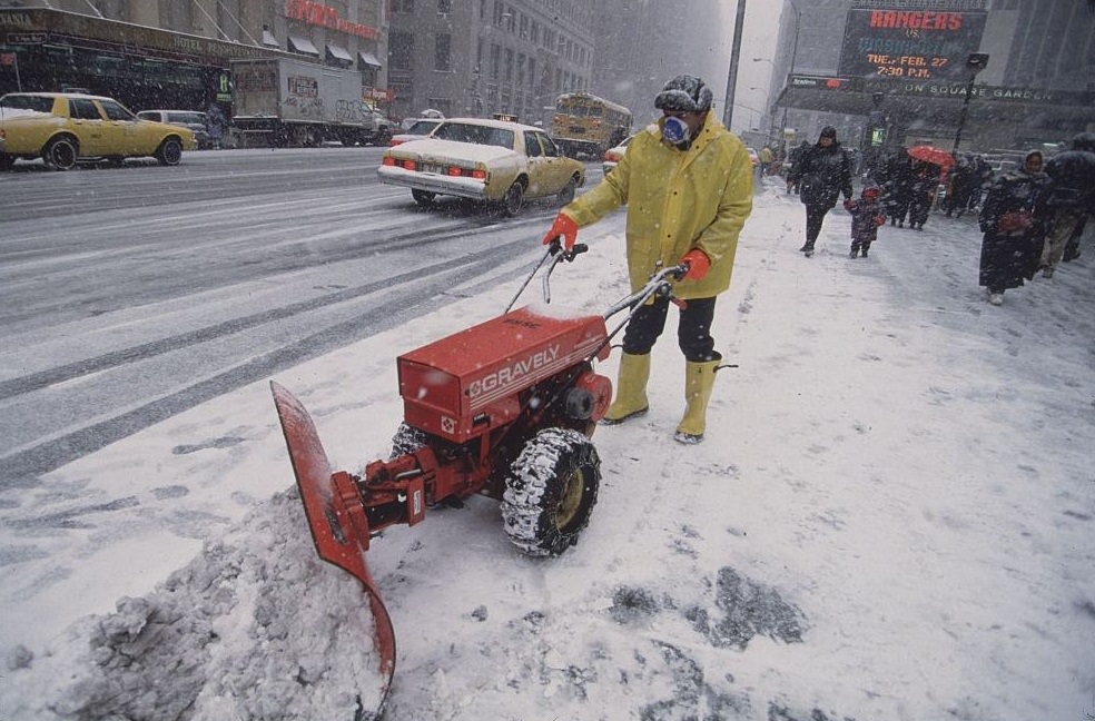 Man in Yellow Coat and Boots Using Electric Snowplow, 1996