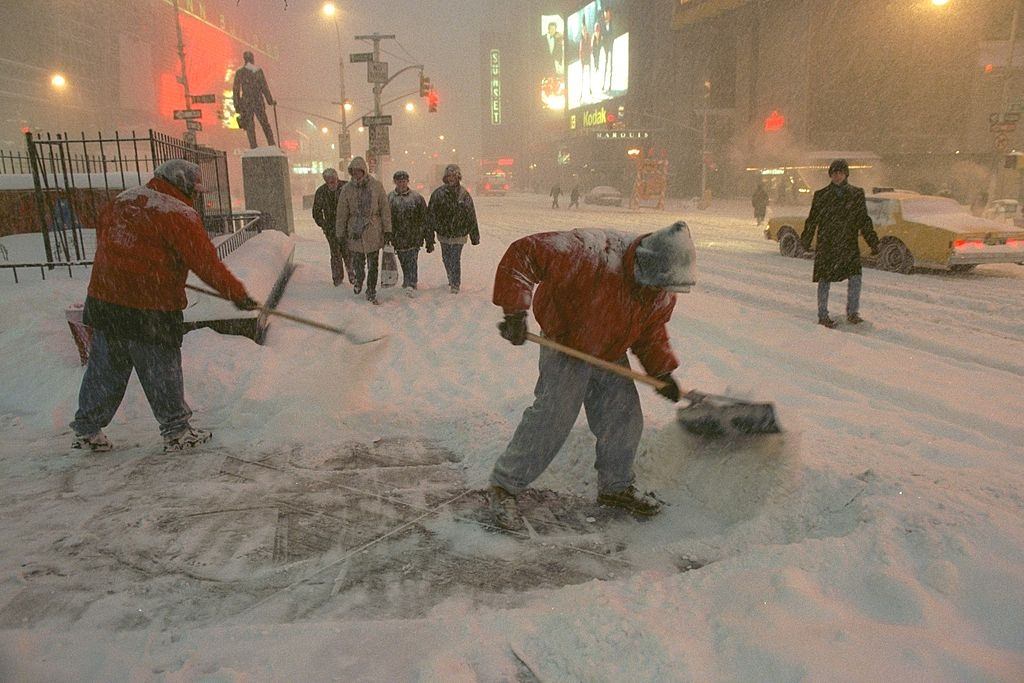 Workers shovel snow from the sidewalk in Times Square during, New York City, 1996