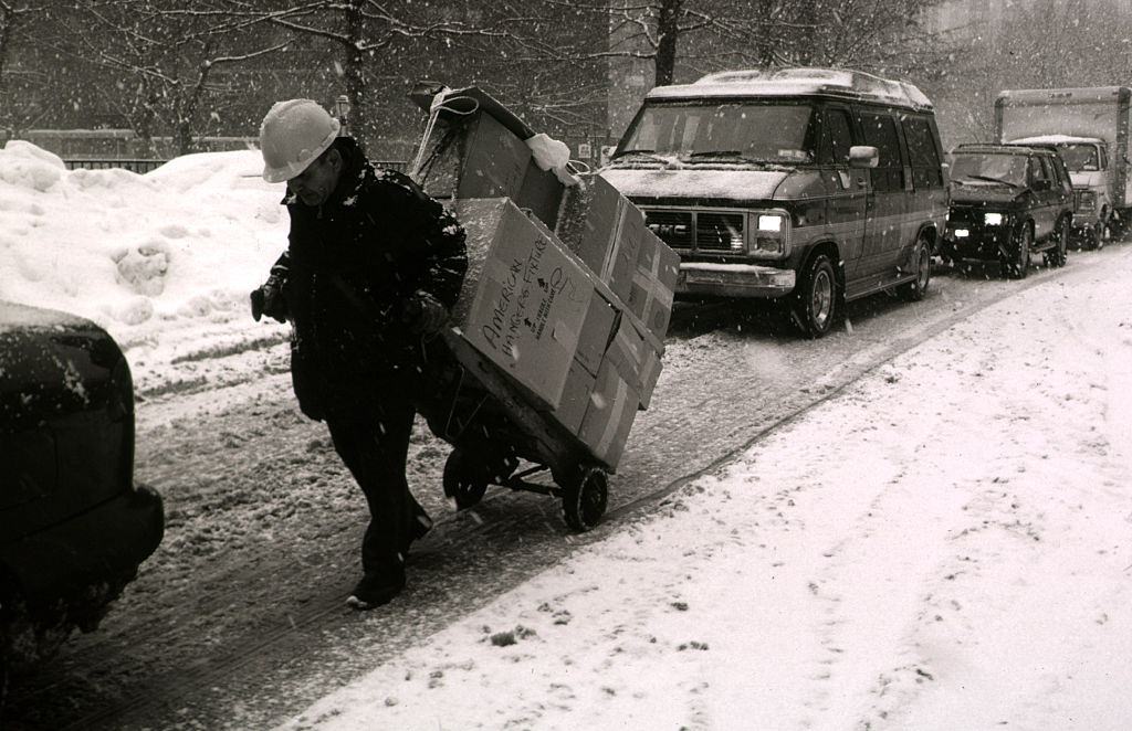 A delivery of goods is pulled by hand in the middle of snow bound traffic during one of the worst blizzards in New York City's history.