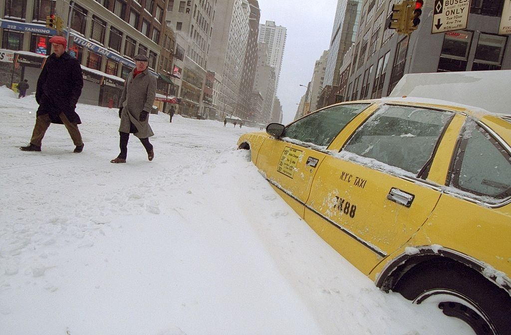 Idle taxi cab sits buried in snow on 57th St. the day after a blizzard, 1996