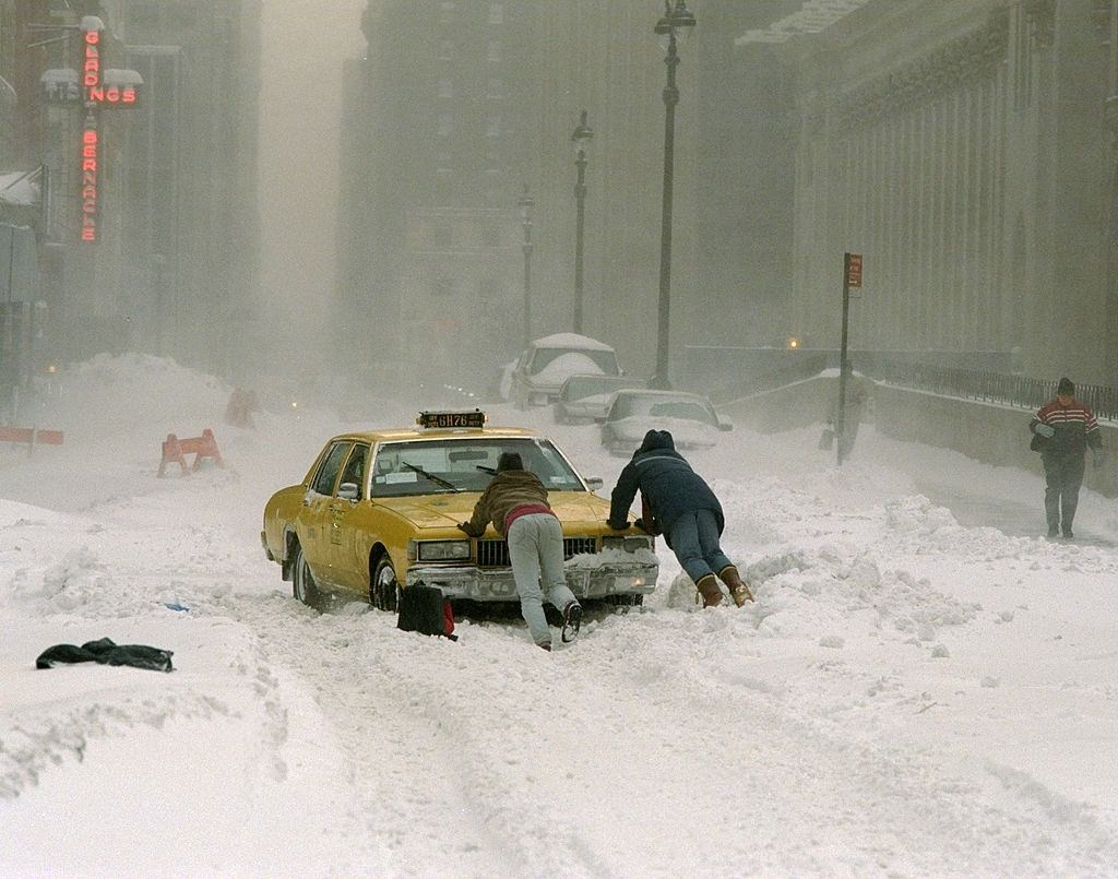 Cab driver pushes his taxi cab after getting stuck on 33rd St. near Ninth Ave. after a blizzard.