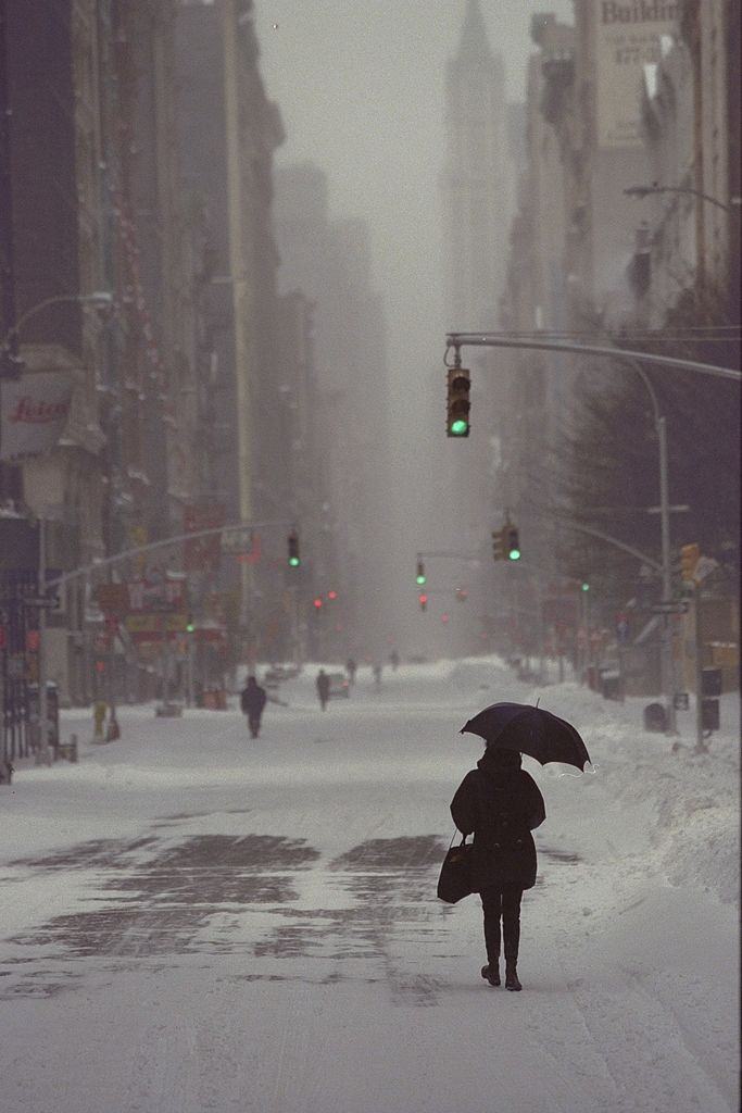 Pedestrian walks down the middle of the street as she makes her way downtown. Sidewalks were piled up with snow after a blizzard.