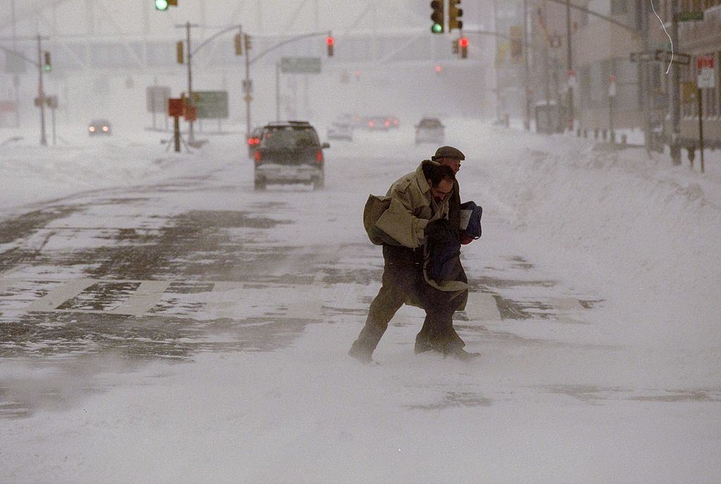 Pedestrians struggle to cross the street during a blizzard.