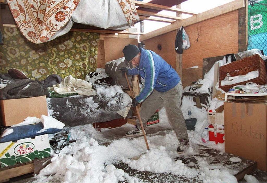 Ron Foster, 56, a homeless resident of New York City, sweeps snow out of his make-shift shelter on South street in Manhattan