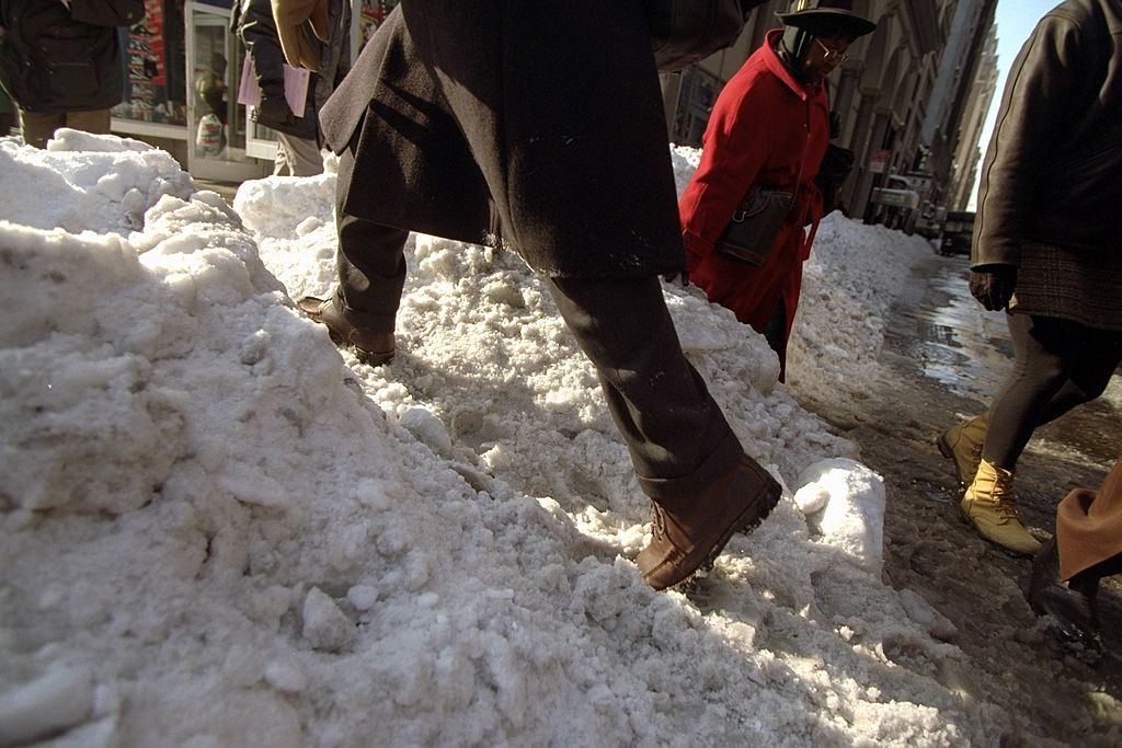 New Yorkers climb mound of snow at the curb as they begin to head back to work after a blizzard.