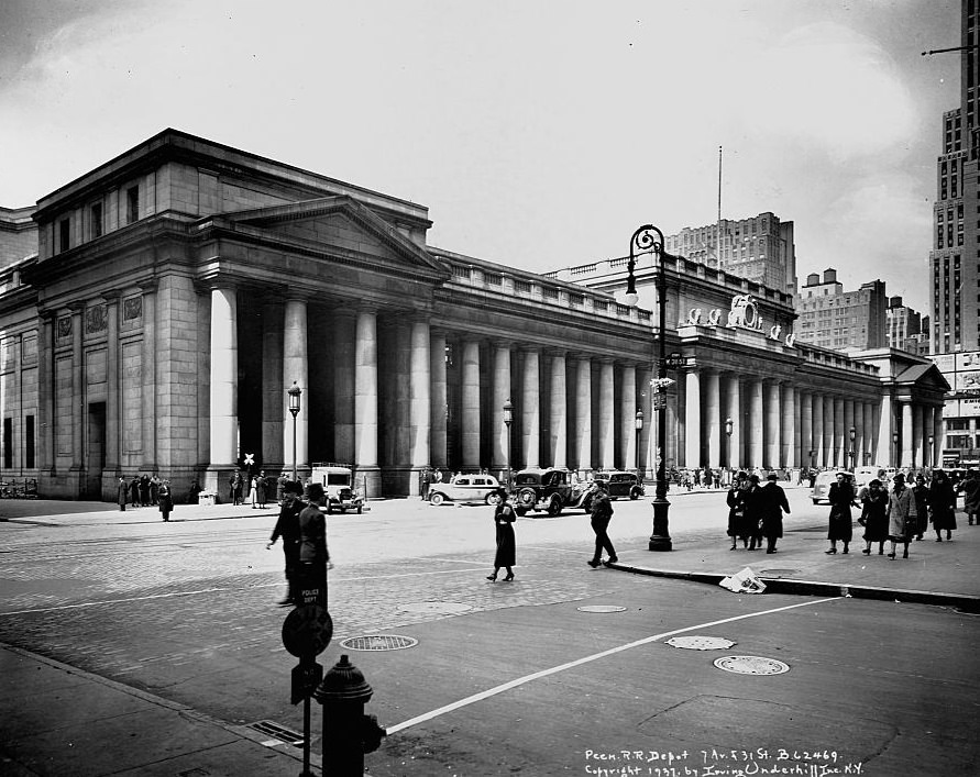Pedestrians and cars bustle past the doric colonnade of Pennsylvania Station.