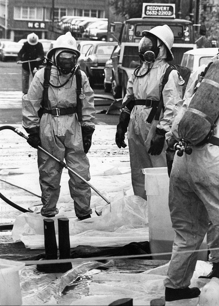 Firemen clad in protective clothing were called to neuralise the acid, 1970s