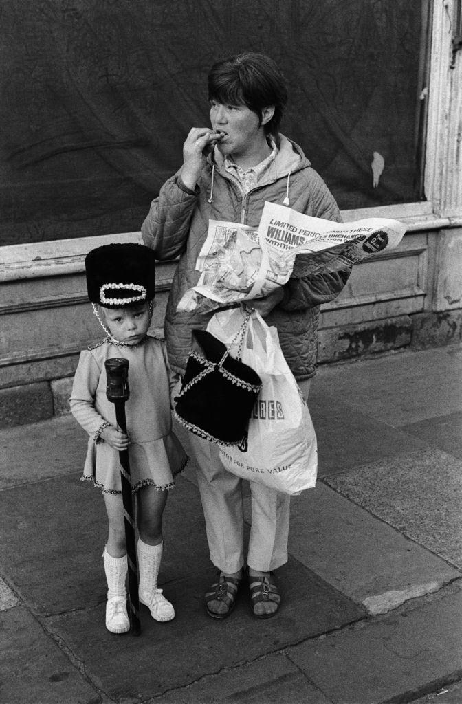 A little girl in a drum majorette costume with her mother, who is carrying another Majorette's military style hat, in Newcastle Upon Tyne, 1973.