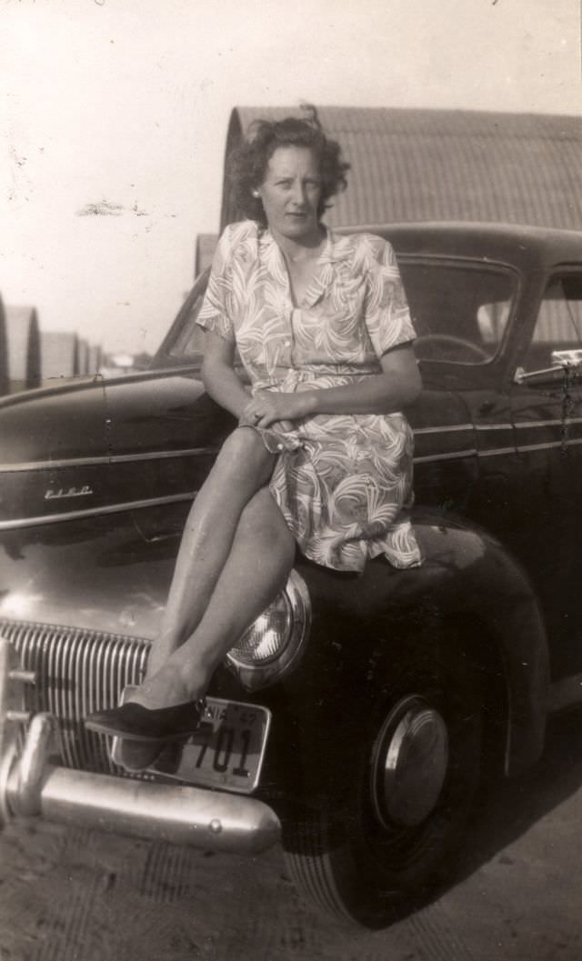 A woman sitting on the fender of a 1941 Studebaker Champion.