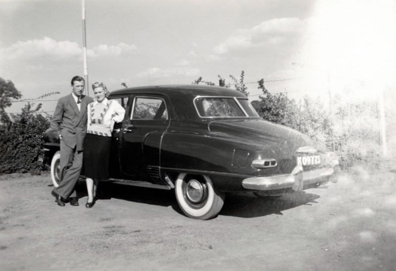 A stylish couple posing with a 1948 Studebaker Champion Regal DeLuxe in the countryside, 1955