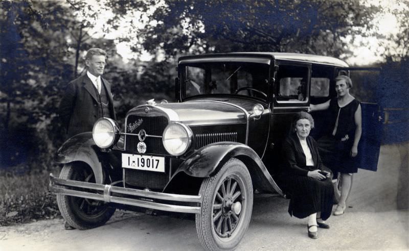 Three members of a German middle-class family posing with a 1928 Erskine by Studebaker on a gravel road in the countryside, July 14, 1929
