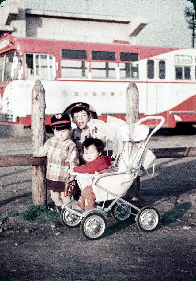 Two Japanese kids in Yomiuri Giants caps and one in a stroller