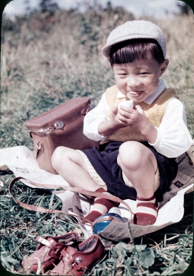 Young boy in a knit vest and a cap eating