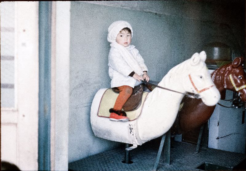 Young girl in a hat riding a toy horse