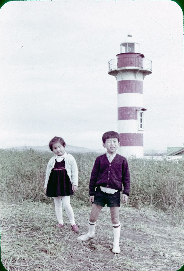 A boy and a girl standing in front of a lighthouse